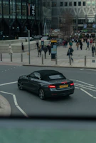 A Volvo convertible cruising along a city street with skyscrapers in the background.