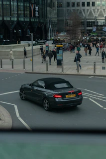 A Volvo convertible cruising along a city street with skyscrapers in the background.