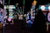 Dimly lit arcade scene with various brightly colored neon lights from different game machines. Several arcade machines, including Monopoly-themed and a large Connect Four game, line the room. The floor has a colorful carpet pattern, and overhead lights create a lively atmosphere.