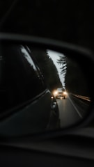 a car's rear view mirror reflecting a car's headlights