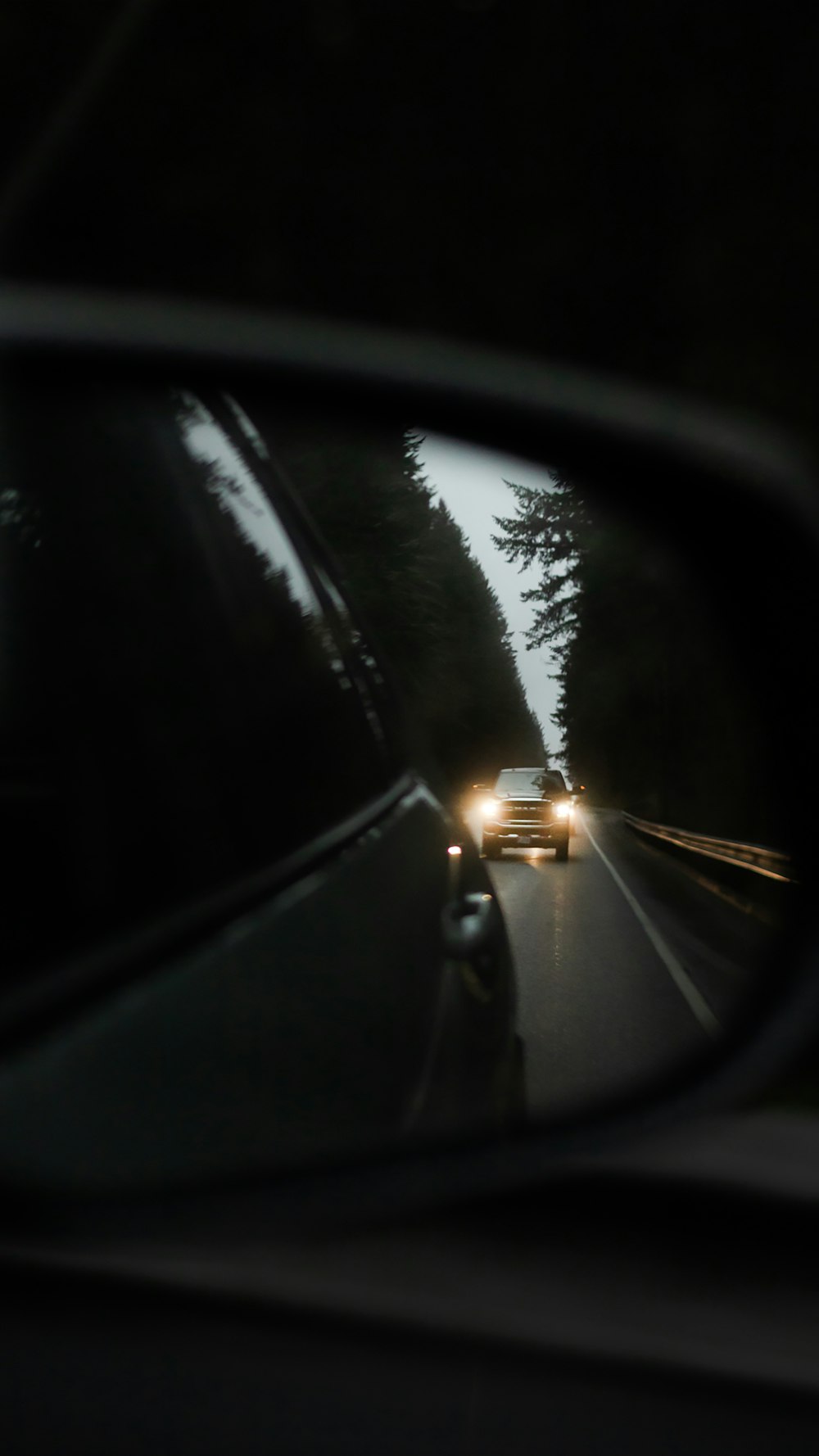 a car's rear view mirror reflecting a car's headlights