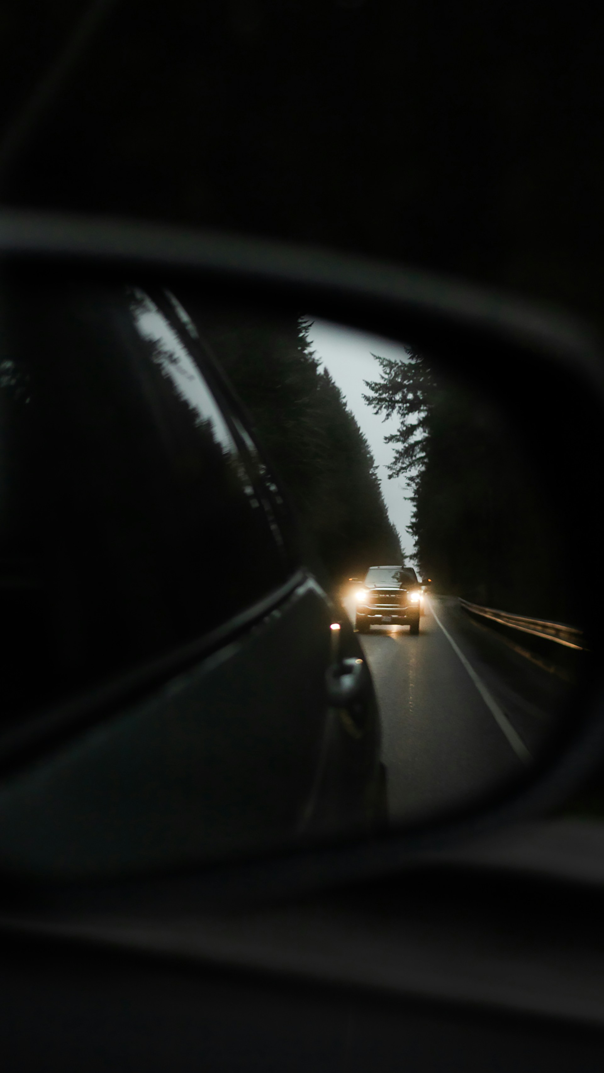 a car's rear view mirror reflecting a car's headlights