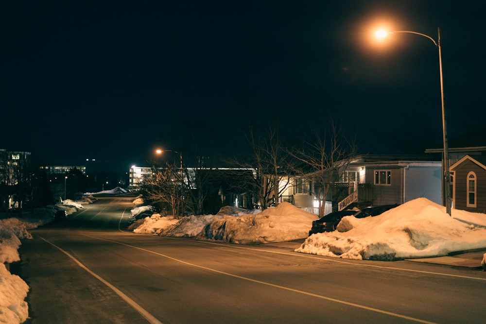 a street at night with snow piled on the side of the road