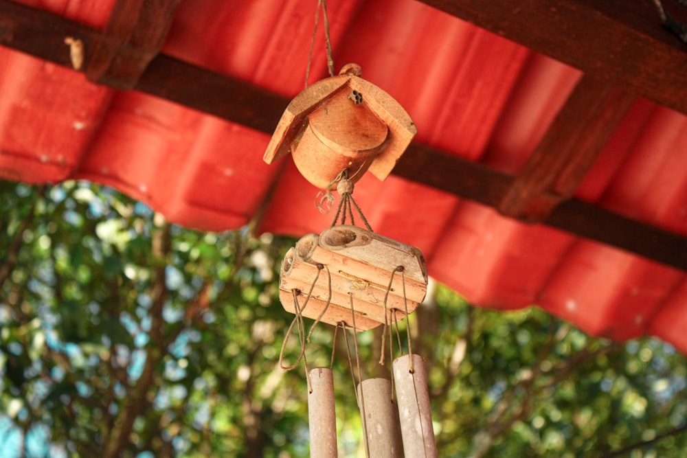 a wooden wind chime hanging from a red roof