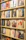 A display shelf filled with vinyl records, each showcasing album artwork. The records are neatly organized on wooden shelves, and the covers feature various artists and designs, ranging from portraits to abstract art.