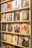 A display shelf filled with vinyl records, each showcasing album artwork. The records are neatly organized on wooden shelves, and the covers feature various artists and designs, ranging from portraits to abstract art.