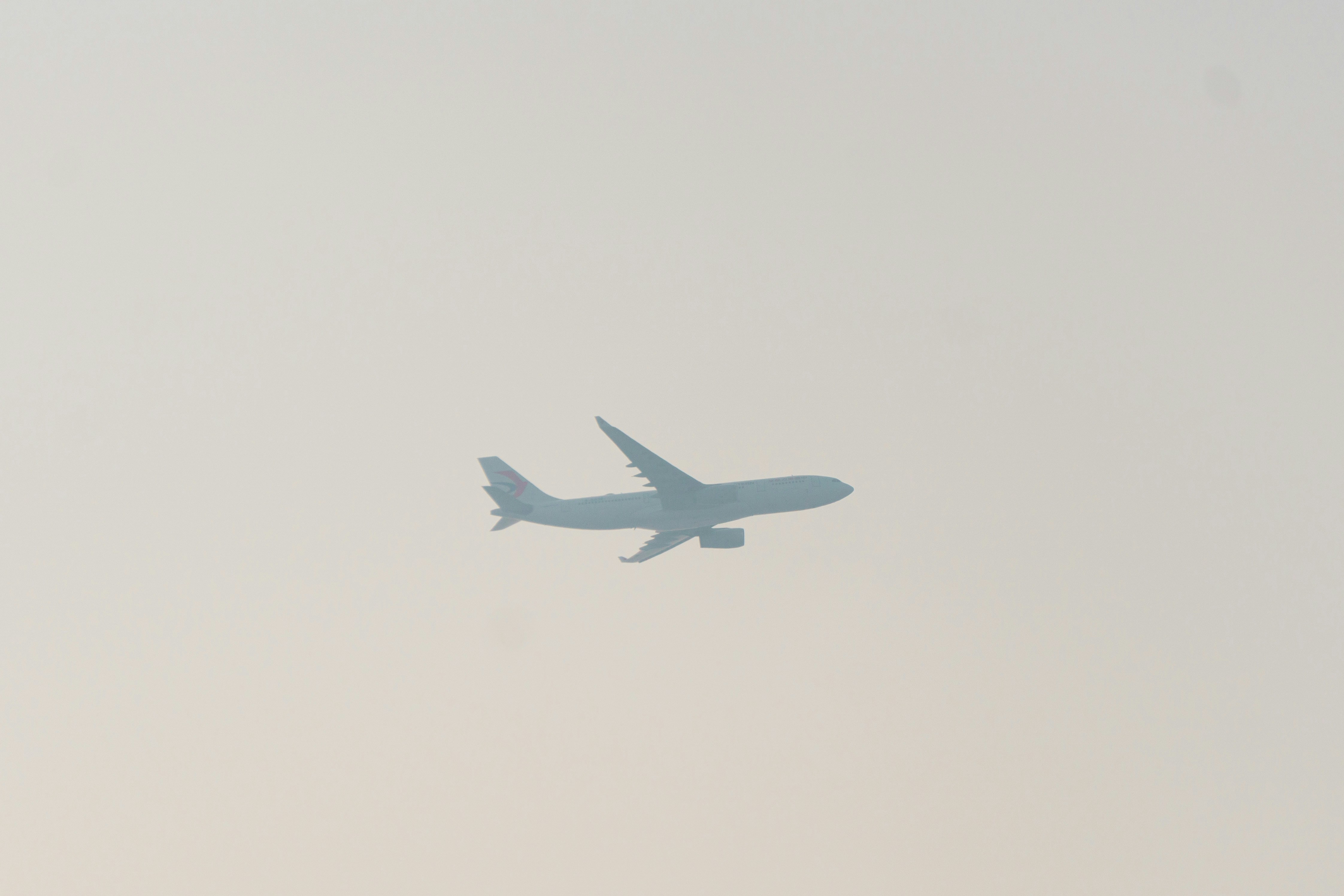 a large jetliner flying through a cloudy sky, 