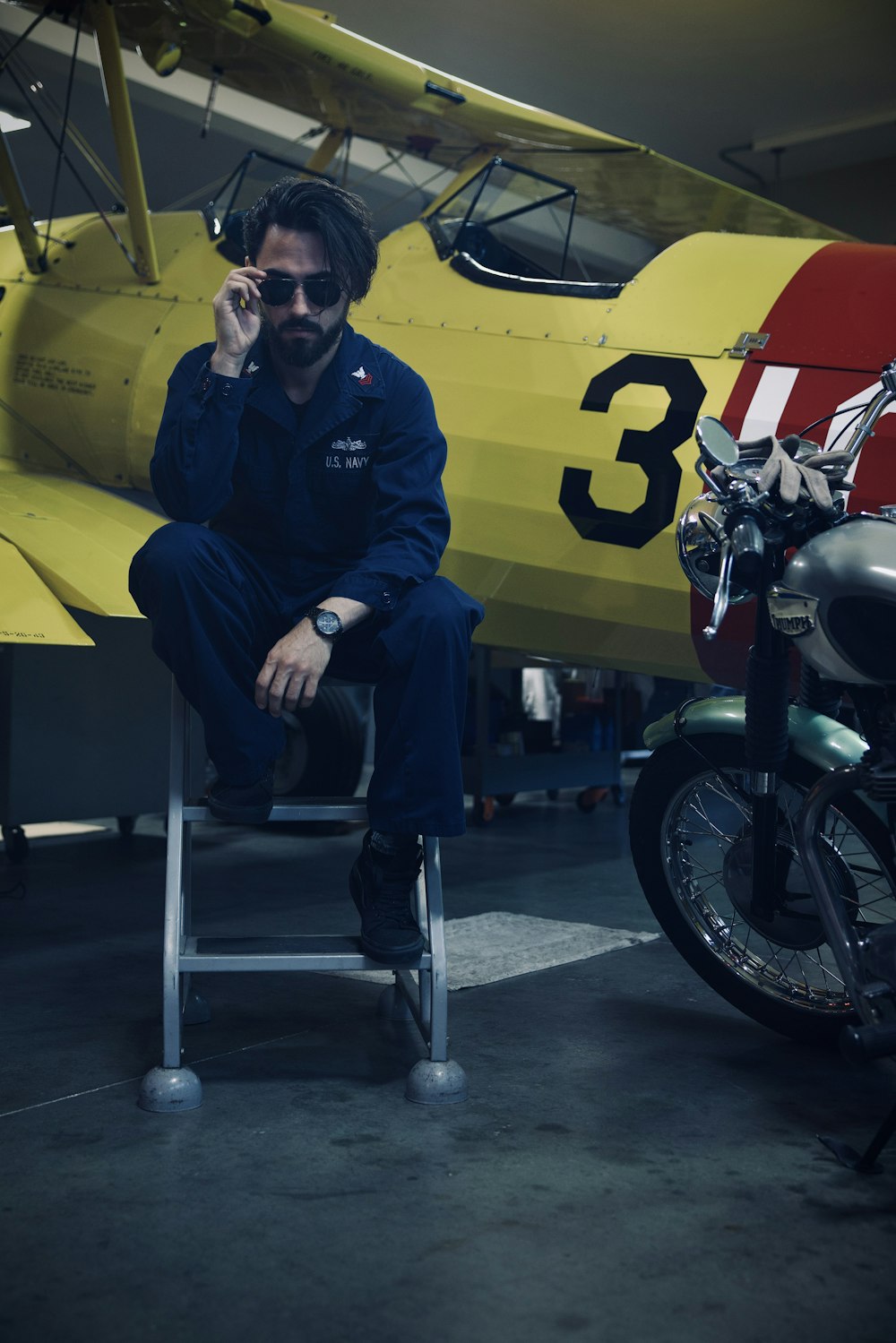 a man sitting on a stool next to a motorcycle