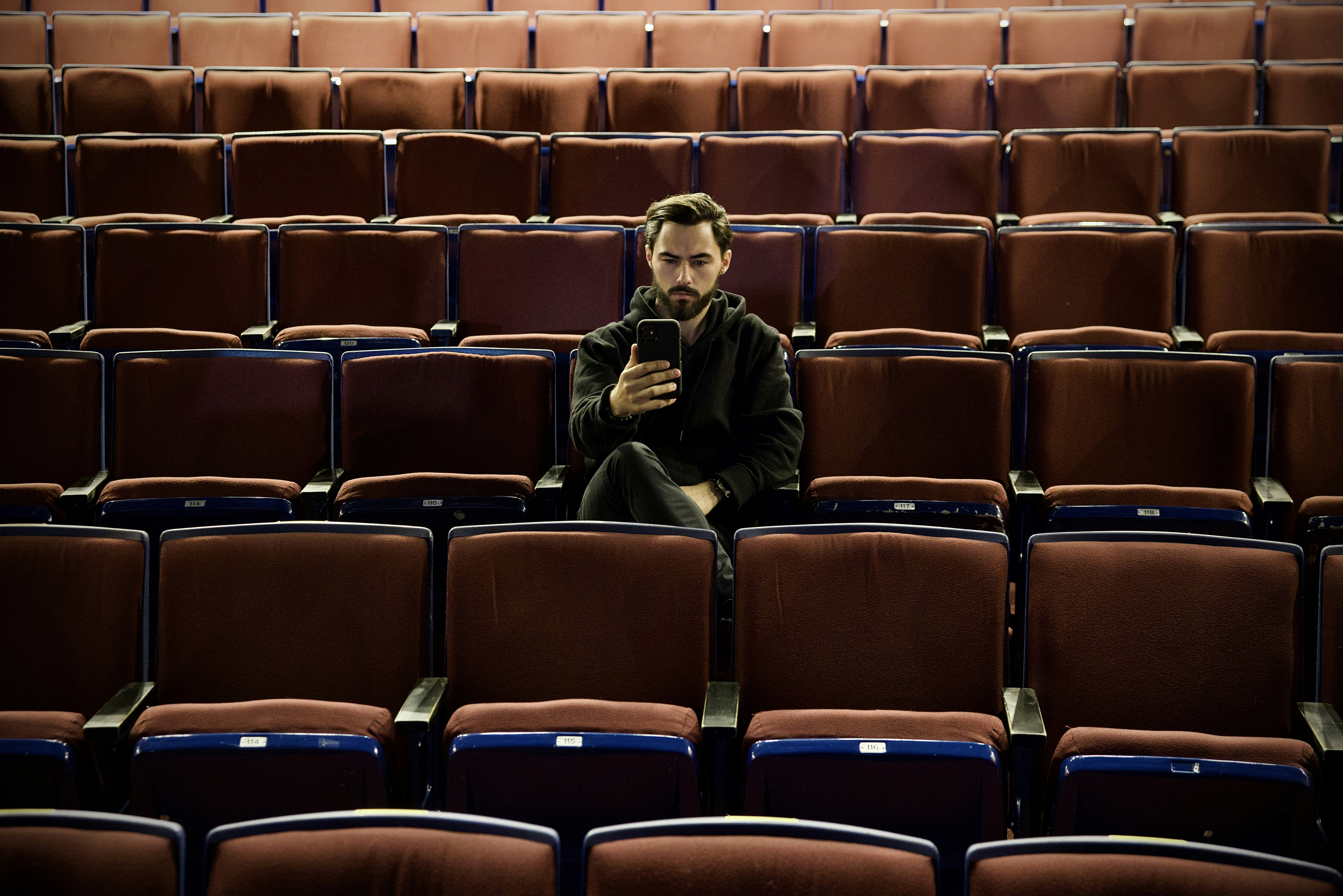 a man sitting in a theater looking at his cell phone