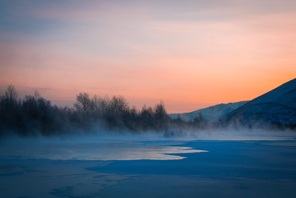 the sun is setting over a frozen lake