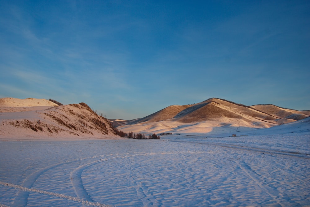 a snow covered field with mountains in the background