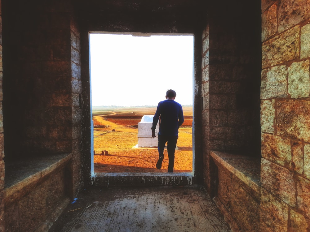 a man standing in a doorway looking at a car