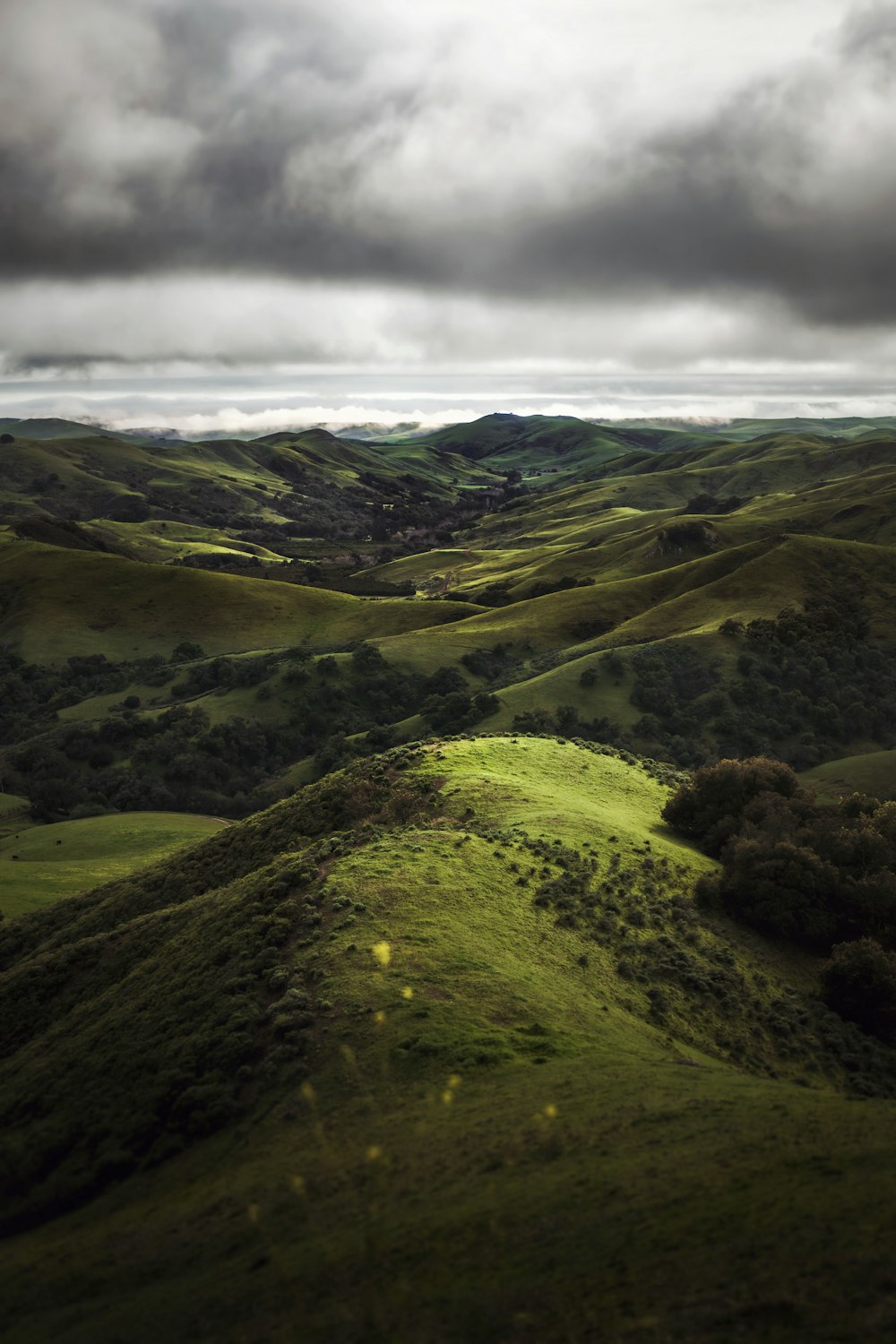 an aerial view of rolling green hills under a cloudy sky