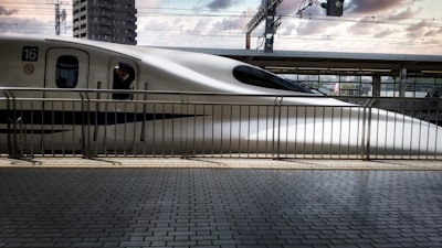 a white train traveling down train tracks next to a tall building