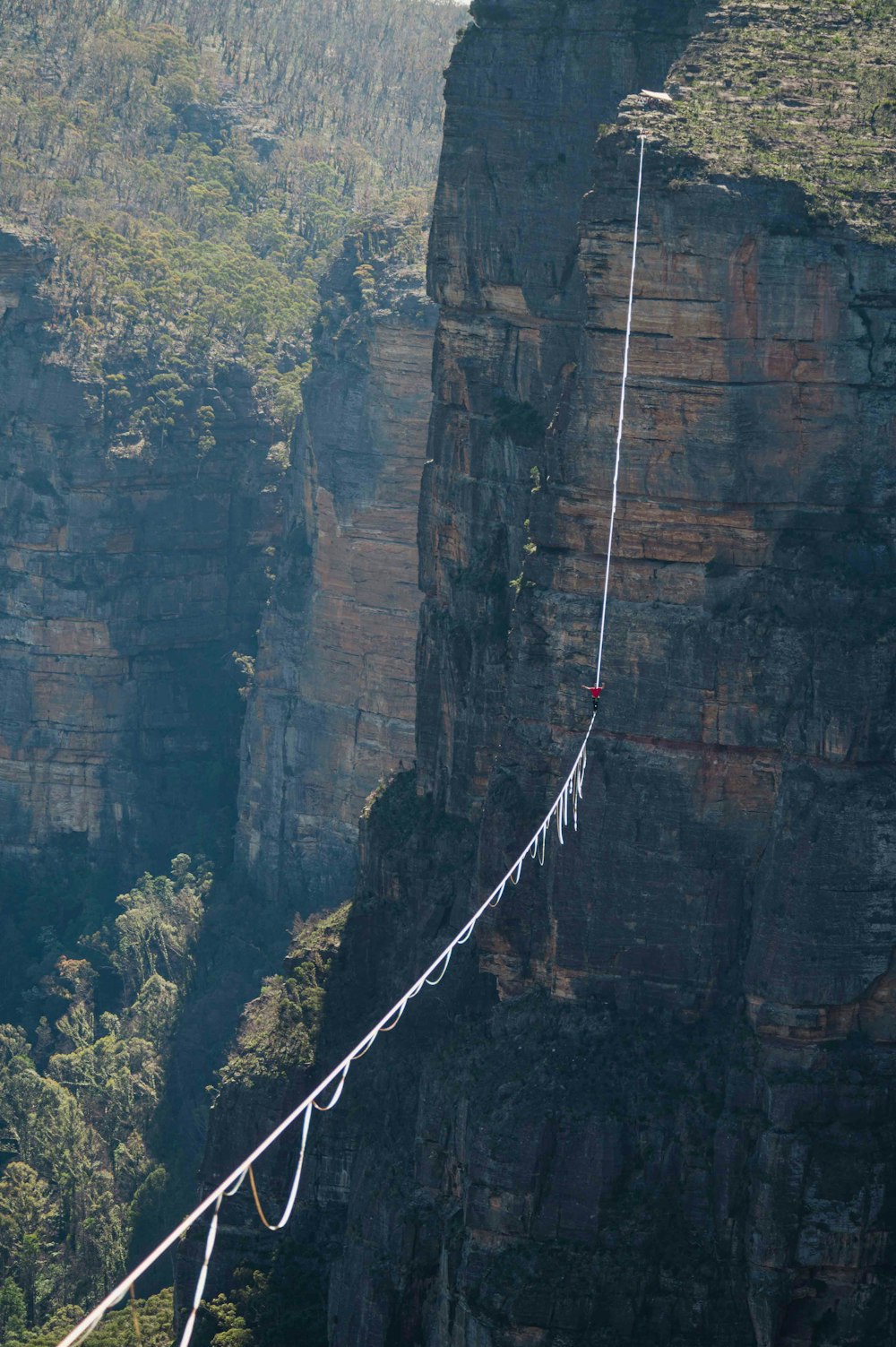 a man walking across a rope over a cliff