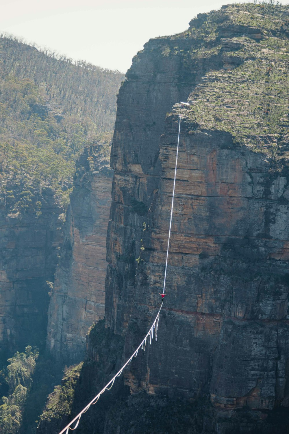 a person on a rope attached to the side of a mountain