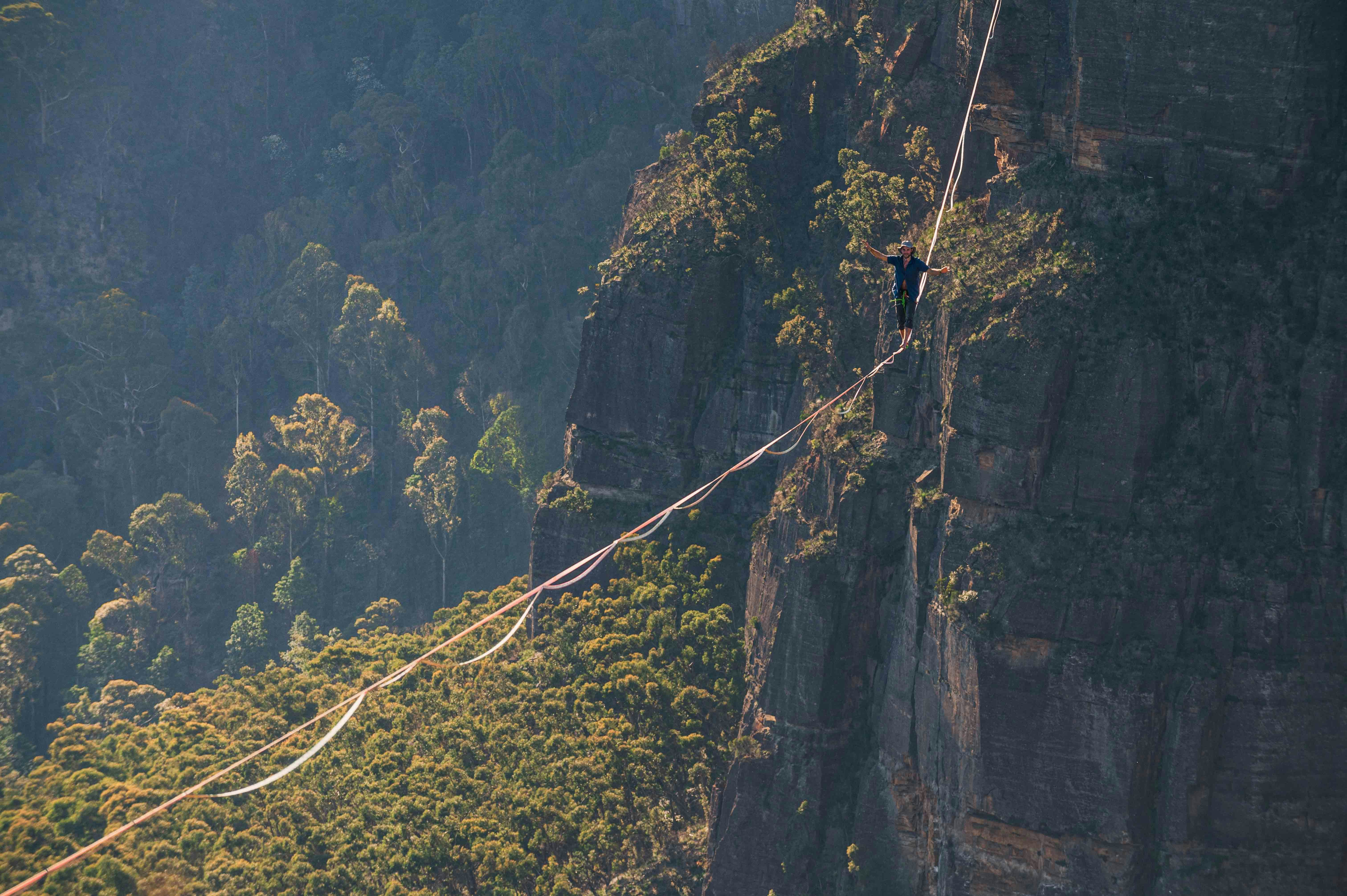 a person walking across a rope over a mountain