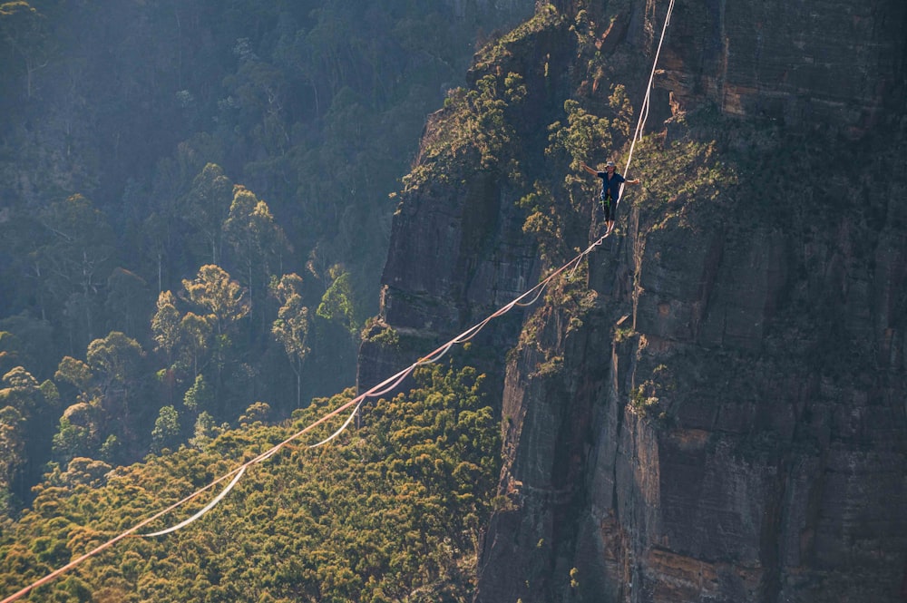 a person walking across a rope over a mountain
