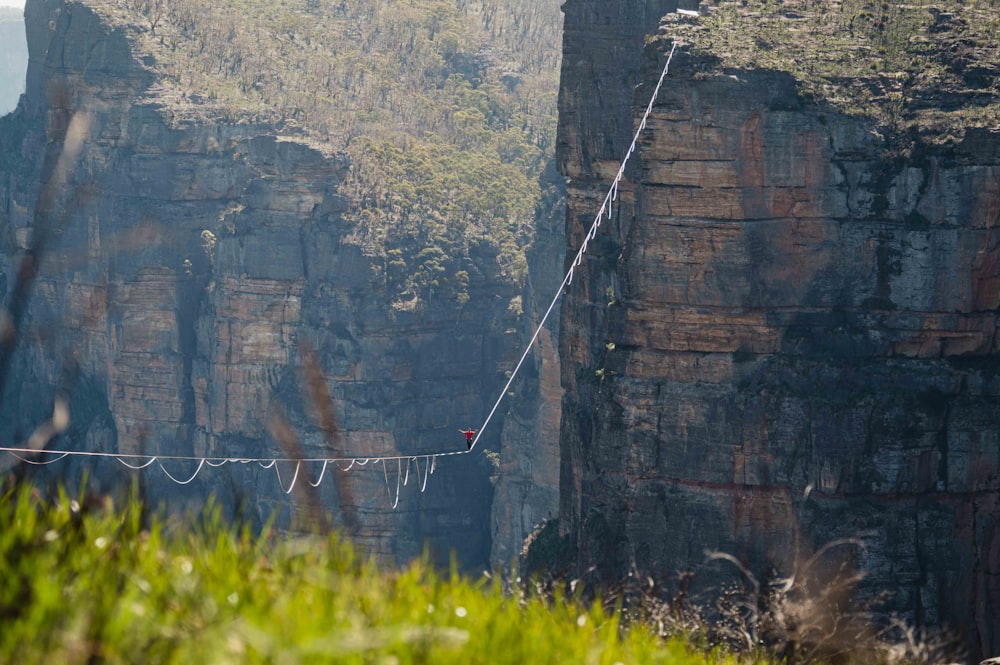 a person walking across a rope over a cliff