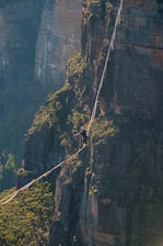 a man walking across a rope on top of a mountain
