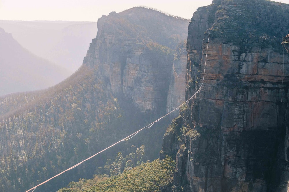 a man walking across a rope bridge in the mountains