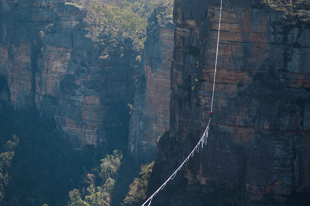 a man walking across a rope over a canyon
