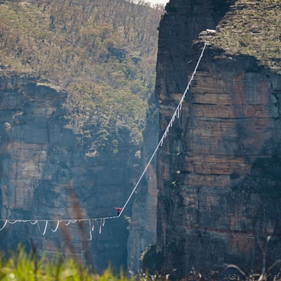 a man walking across a rope bridge over a river