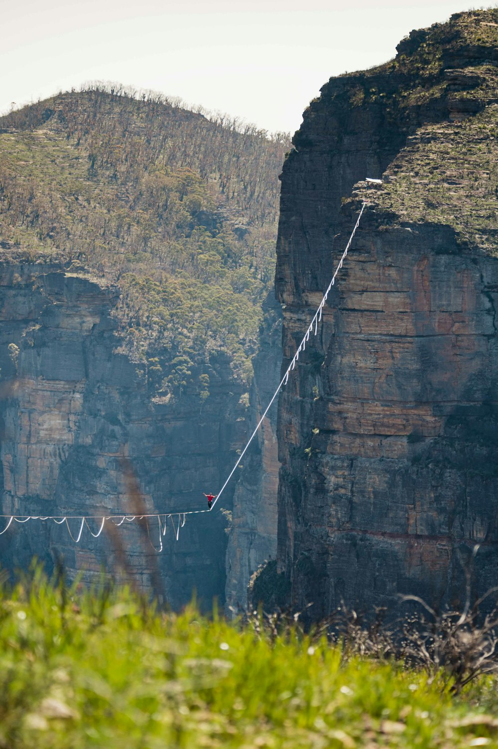 a man walking across a rope bridge over a river