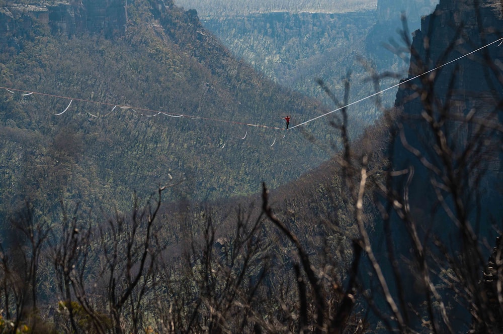 a person walking across a high wire above a valley