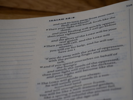 A close-up view of a page from a book, showing text from Isaiah 58 in the Bible. The page has a light background and the text is printed in a clear, dark font. The text includes verses and has a structured layout with verse numbers.
