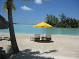 two chairs under a yellow umbrella on a beach