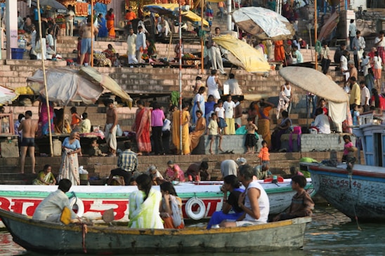 A panoramic view of devotees taking a holy dip in the Godavari River during the Pushkaram festival, with colorful boats and festive decorations.