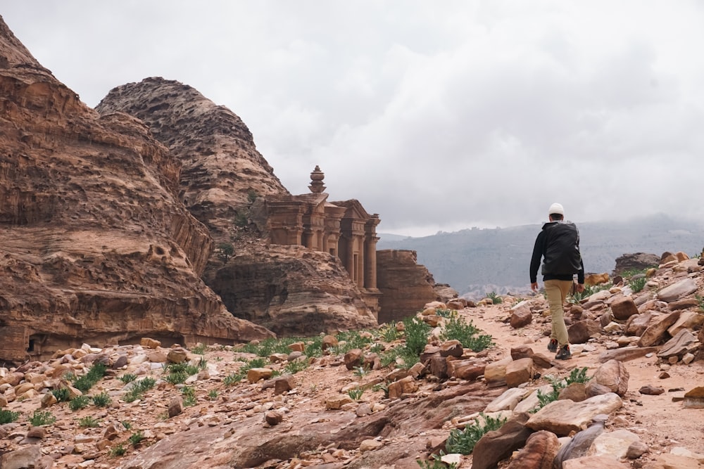 a man walking on a rocky path in the desert