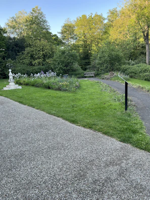 A serene backyard featuring a manicured lawn, trimmed shrubs, and a winding stone pathway.