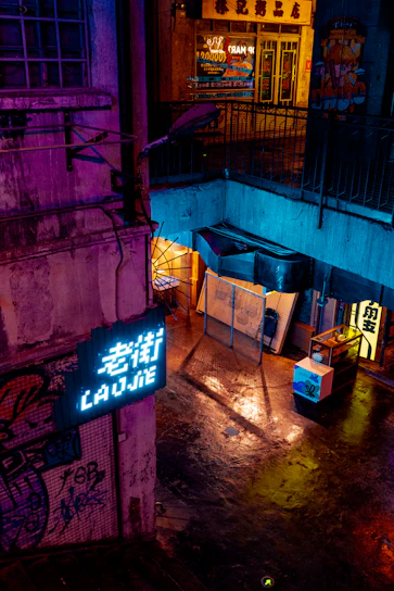 Close-up of a neon-lit alleyway filled with holographic signs and futuristic graffiti under a rainy sky.