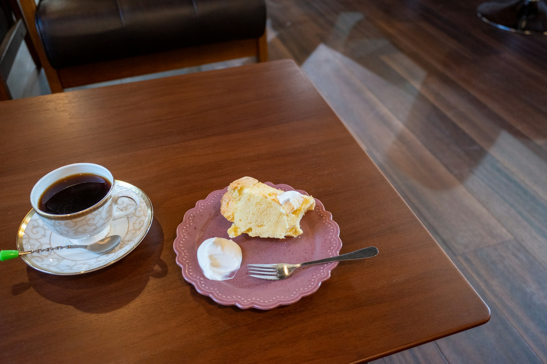 A delicious slice of homemade cake on a rustic wooden table with a steaming cup of coffee.