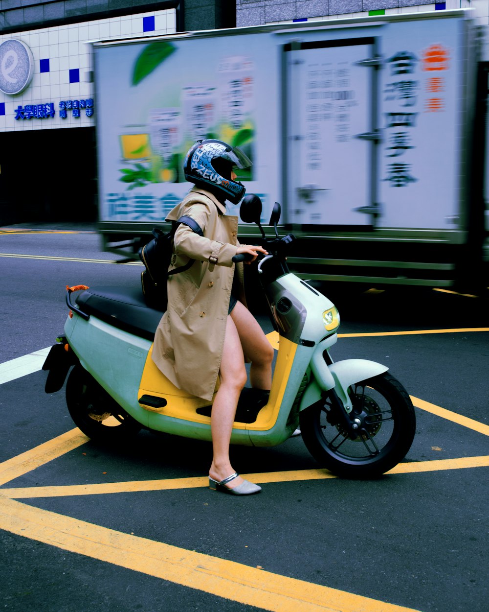 a woman in a trench coat is riding a scooter