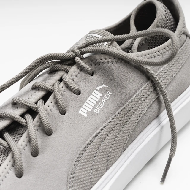 Close up of a gray sneaker with a white sole against a plain background