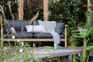 An inviting outdoor loveseat set against a garden backdrop with cozy pillows.