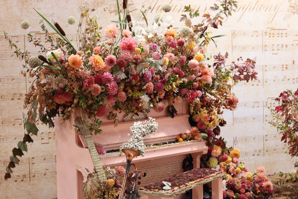 a pink piano with a bunch of flowers on top of it