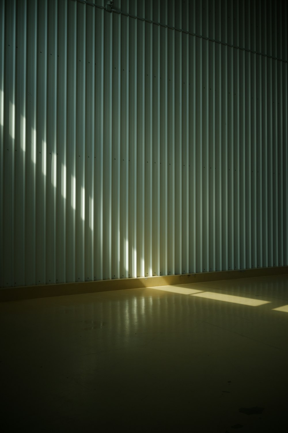 an empty room with a wall made of vertical blinds
