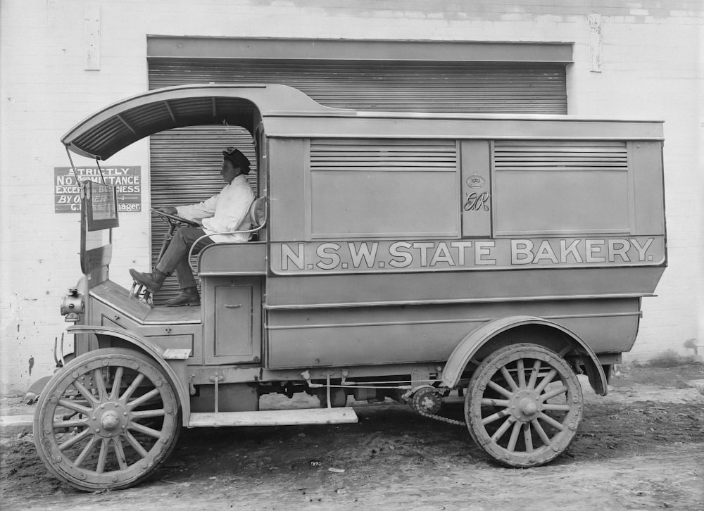 an old photo of a man sitting in the back of a truck