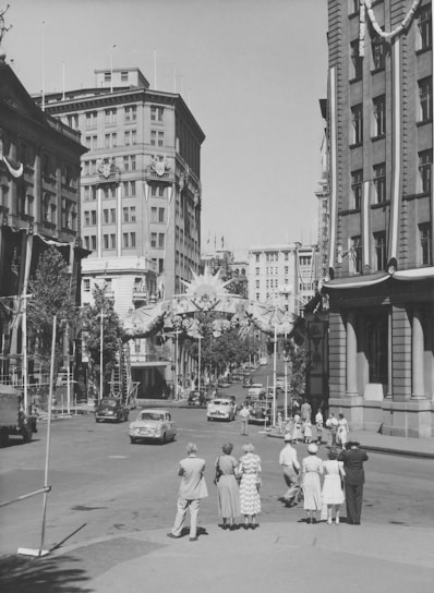 a group of people walking down a street next to tall buildings
