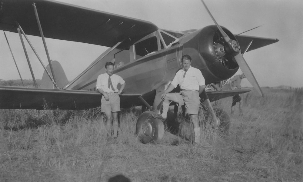 a couple of men standing next to a small plane