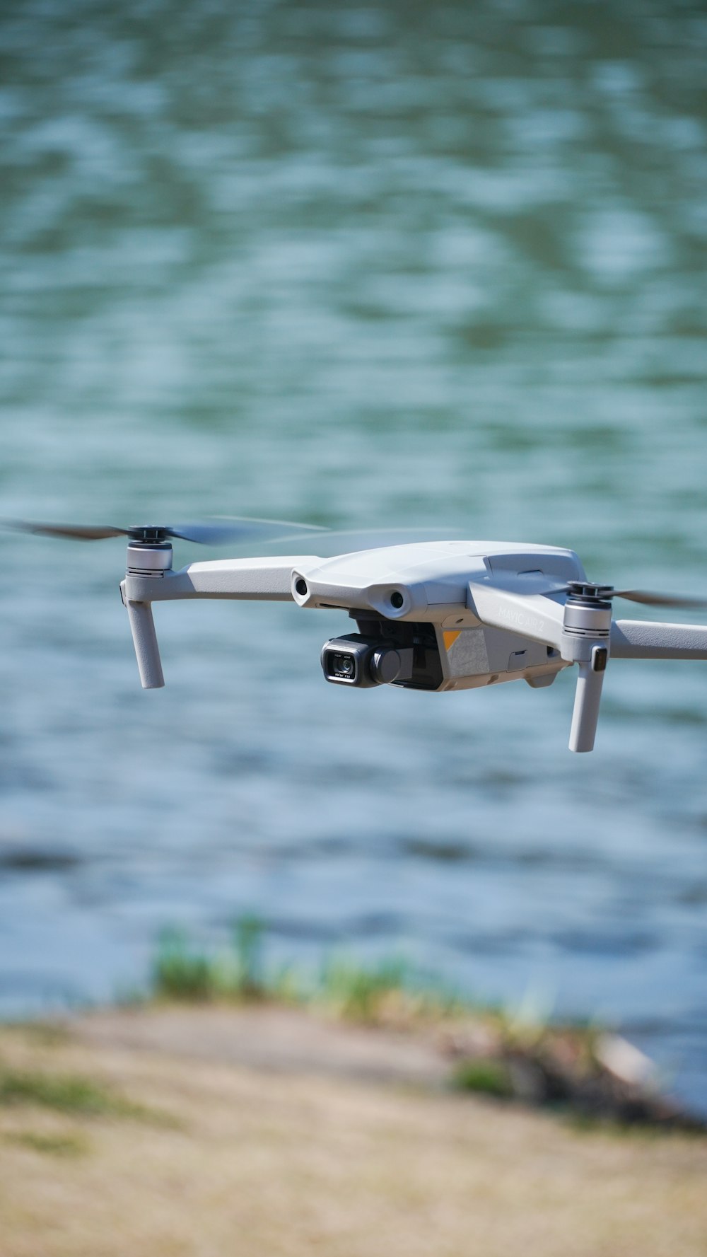 a close up of a white remote control flying over a body of water