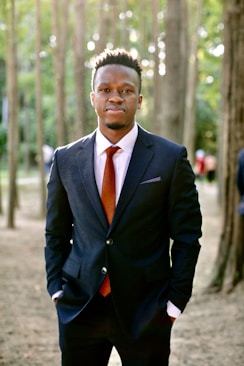 A confident man standing calmly in a natural setting, embodying steady leadership.