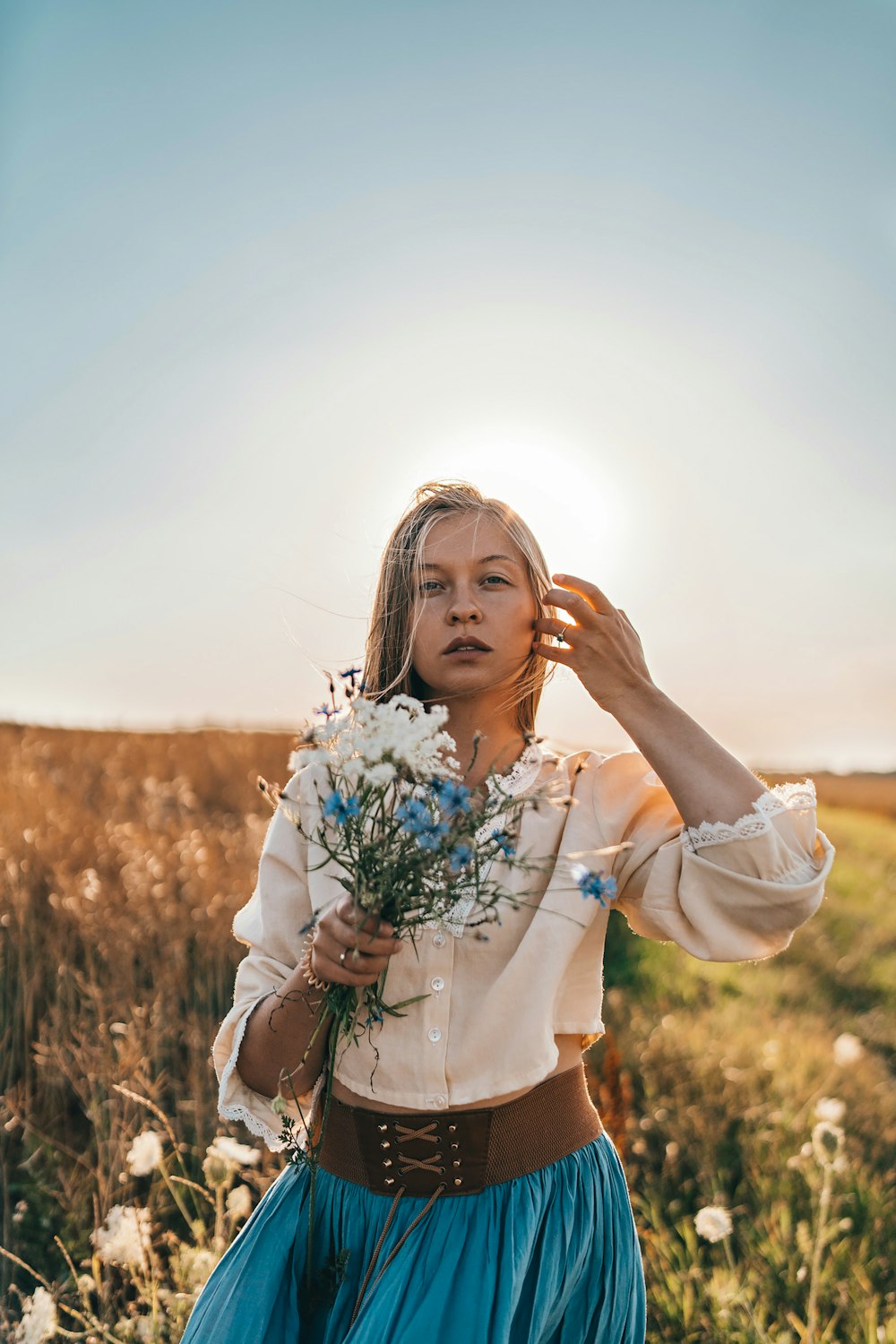 a woman standing in a field holding a bouquet of flowers