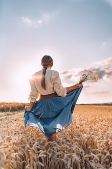 a woman standing in a field holding a bouquet of flowers