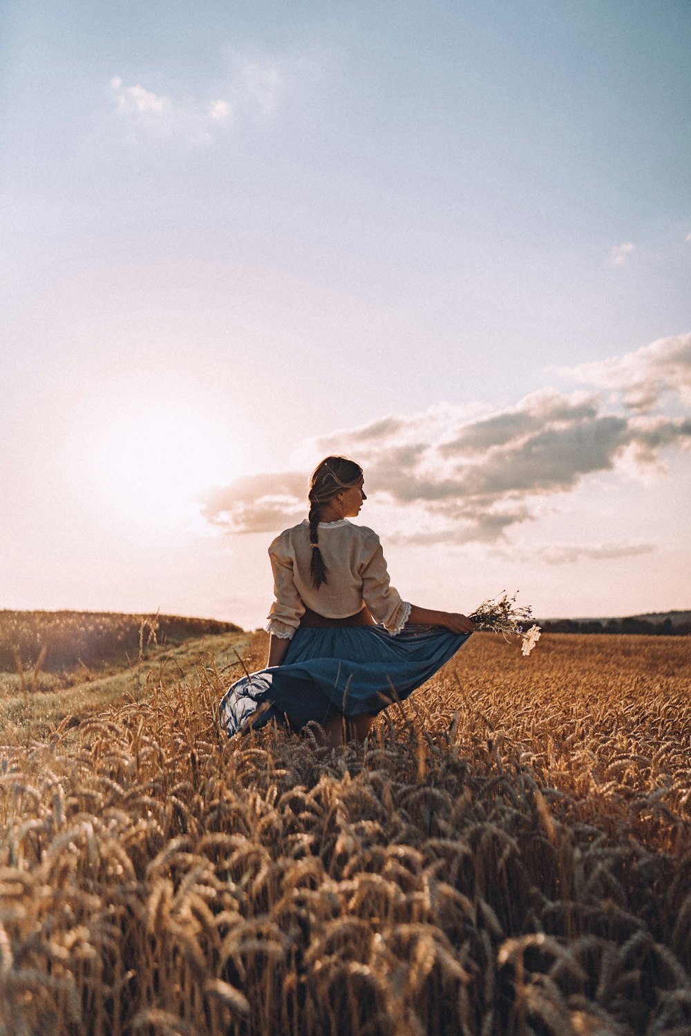 a woman sitting in a field of wheat