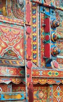 A close-up of traditional artisans crafting intricate truck art designs.